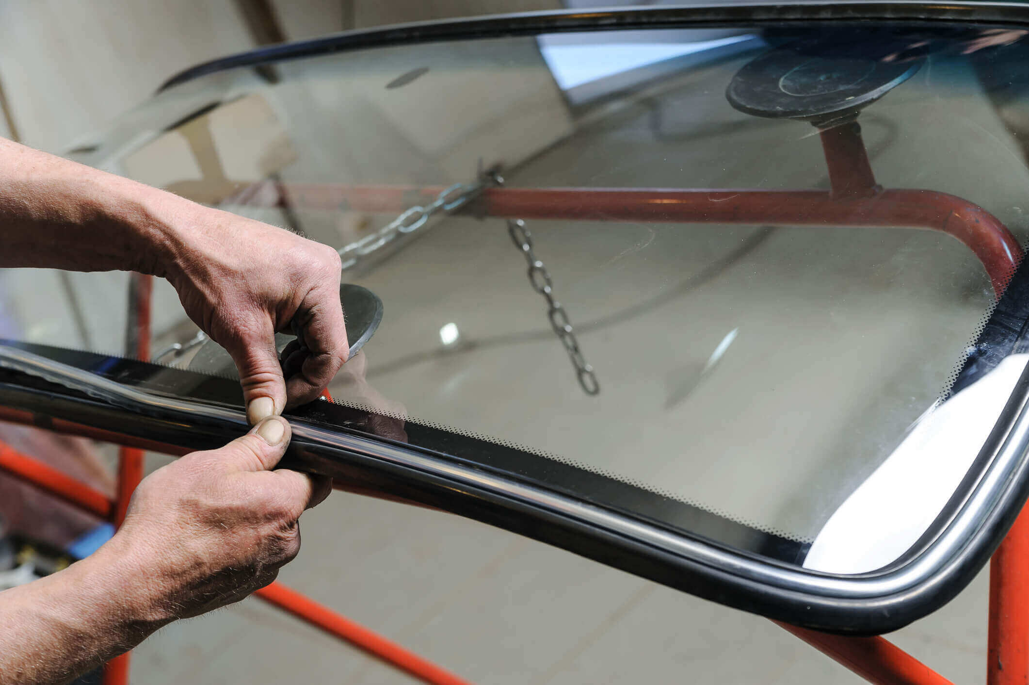 person attaching new car window to frame with adhesive